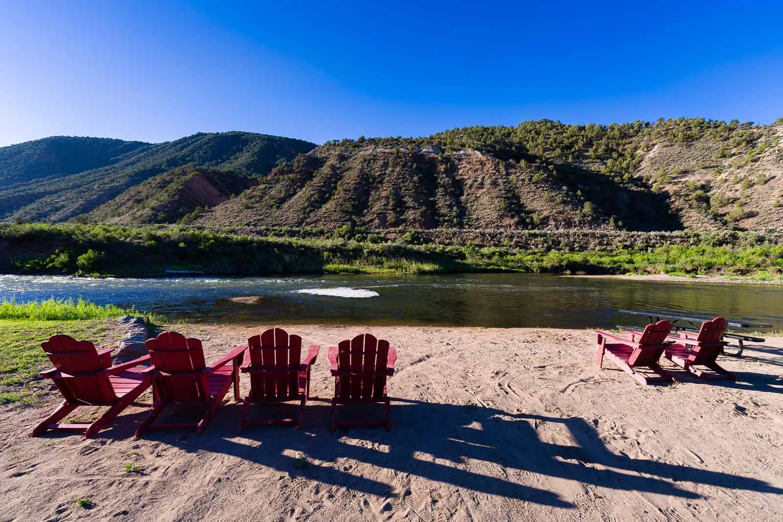 Red Adirondack chairs on the bank of the Eagle River at Riverdance RV Resort in Gypsum, Colorado